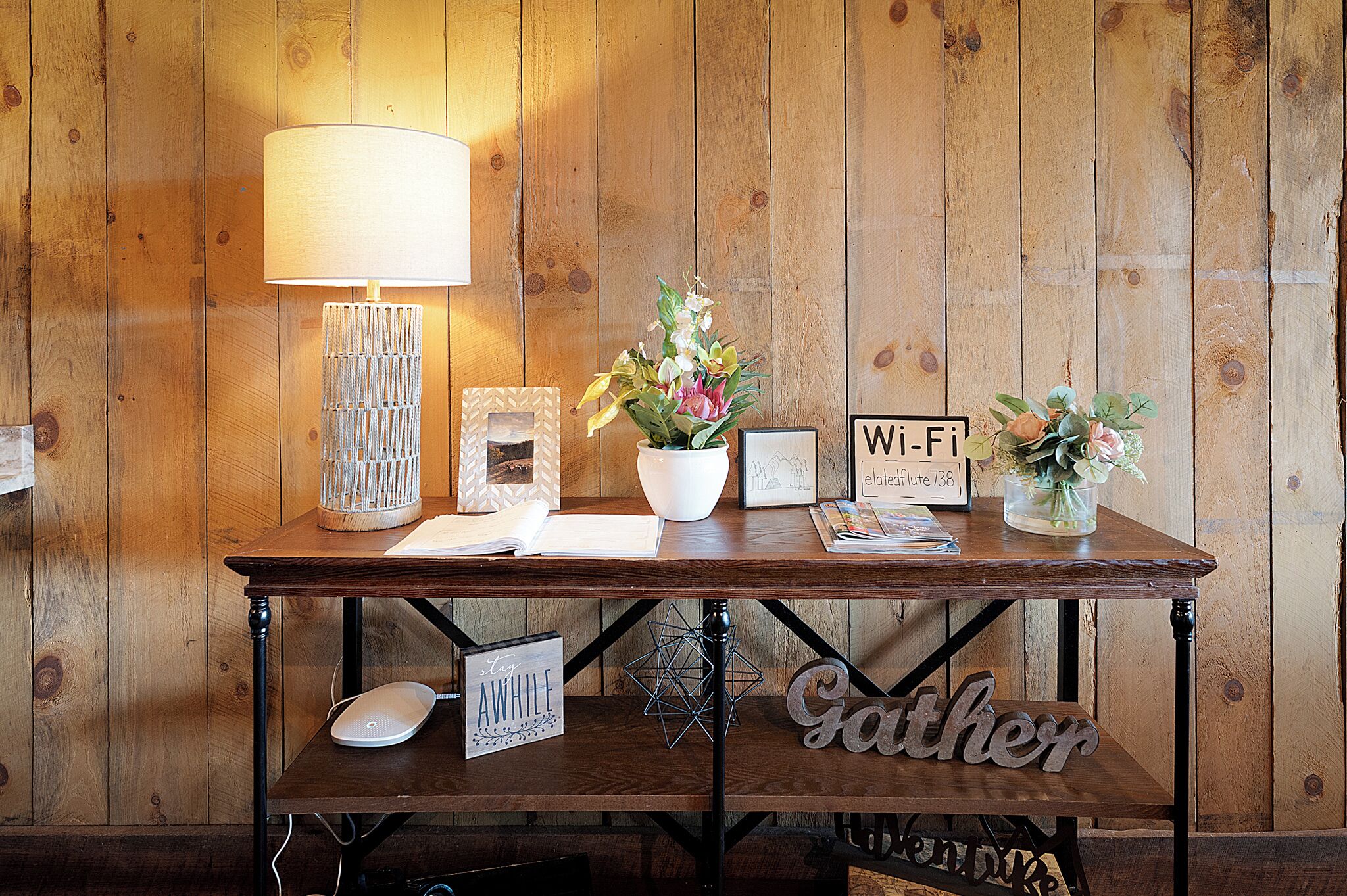 A wooden table with a lamp, a potted plant, a Wi-Fi sign, and a sign that reads 'AWHILF'.