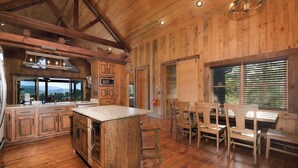 A spacious kitchen with wooden cabinetry, a large island, and a dining area with wooden chairs. - Breakaway Ridge - Mountain Tops (Blue Ridge)