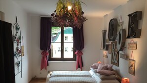 A bedroom with a bed, a window with curtains, a wall with decorative letters, and a hanging light fixture. - Ferienwohnung 3 - Ferienwohnungen in der Kaffeewerkstatt (Sankt Wolfgang im Salzkammergut)