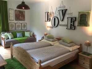 A bedroom with a wooden bed, two bedside tables, a nightstand, a green sofa, and a wall with motivational signs.