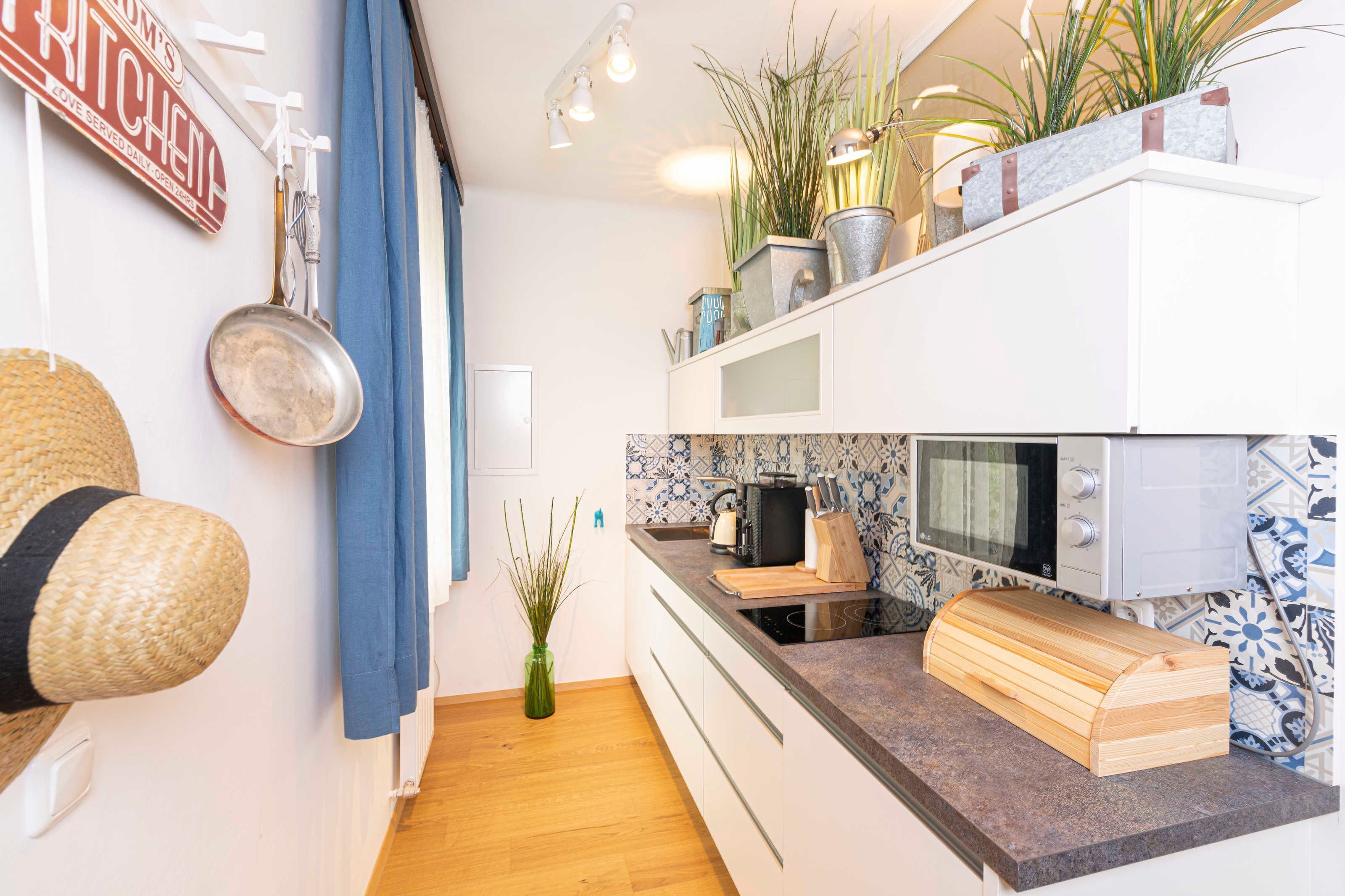A kitchen with white cabinets, a microwave, a toaster, and a wooden cutting board.