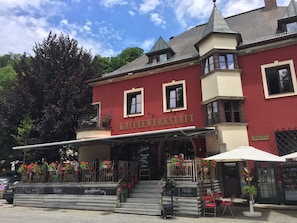 A building with a sign reading 'KAFFEEWERKSTATT' and outdoor seating with tables and chairs.