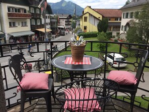 A balcony with a round table, two chairs, and a potted plant.