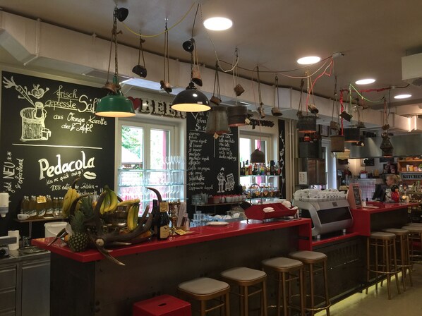 Un espace bar avec des tabourets, un menu écrit à la craie et des lampes suspendues.