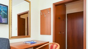 A room with a wooden desk, a chair, a mirror, and a wardrobe.