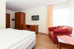 Ett hotellrum med en säng, ett skrivbord, en tv, en soffa och ett bord.