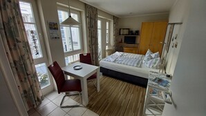 A hotel room with a bed, a desk, a chair, and a wardrobe.