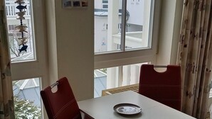 A dining area with a white table, red chairs, and a hanging lamp.