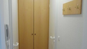 A hallway with a double door closet, a coat hook, and a phone on the wall.