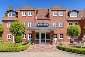 A hotel with a red brick facade, a central entrance with glass doors, and a sign reading "Hotel Benser Watt". - Doppelzimmer im Obergeschoss Kategorie III - Doppelzimmer im Obergeschoss im Hotel Benser Watt (Esens)