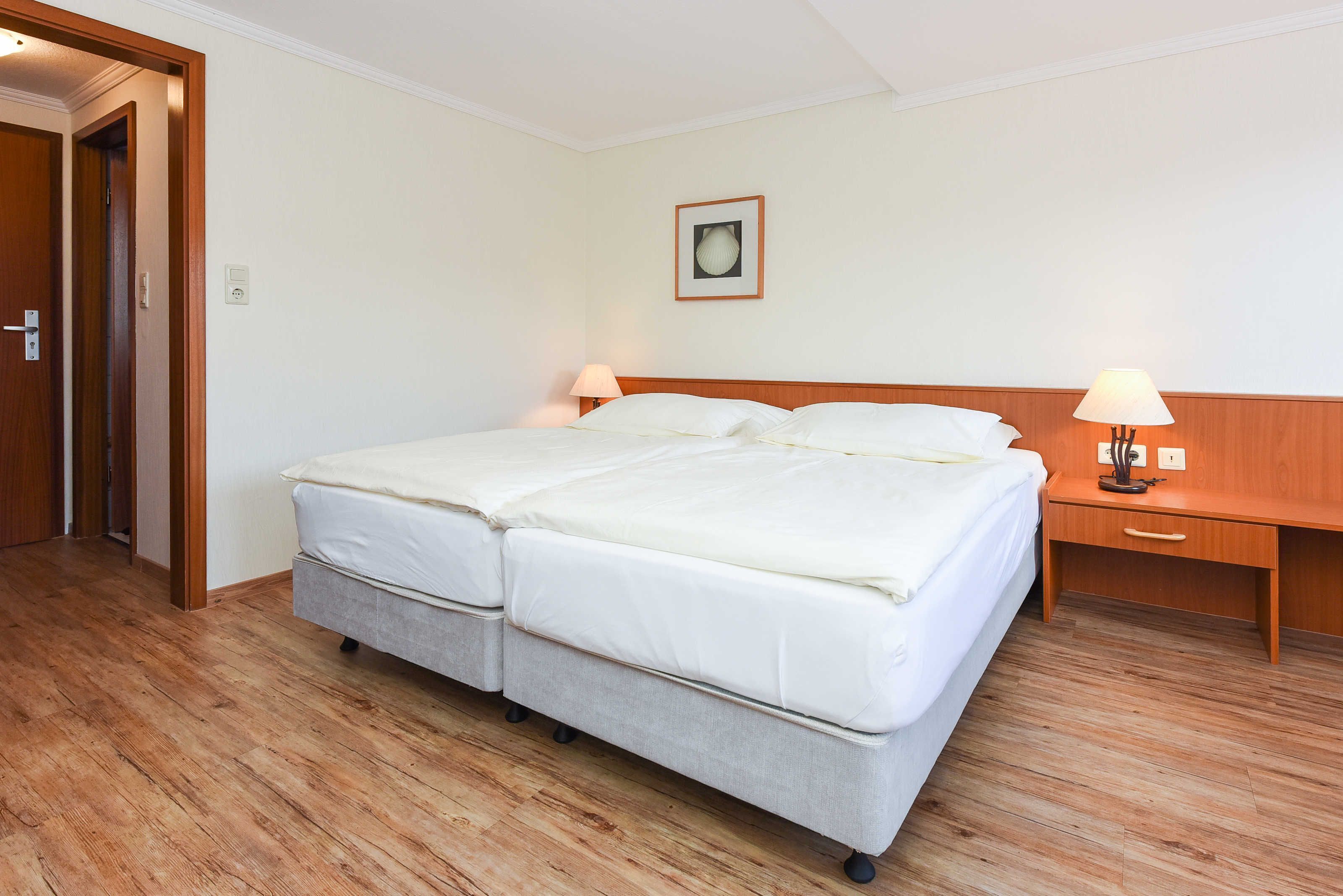 A double bed with a wooden headboard, two bedside tables with lamps, and a framed picture on the wall.
