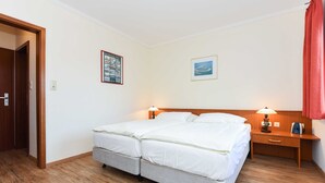 A double bed with two pillows, a nightstand with a lamp, and a wooden headboard.