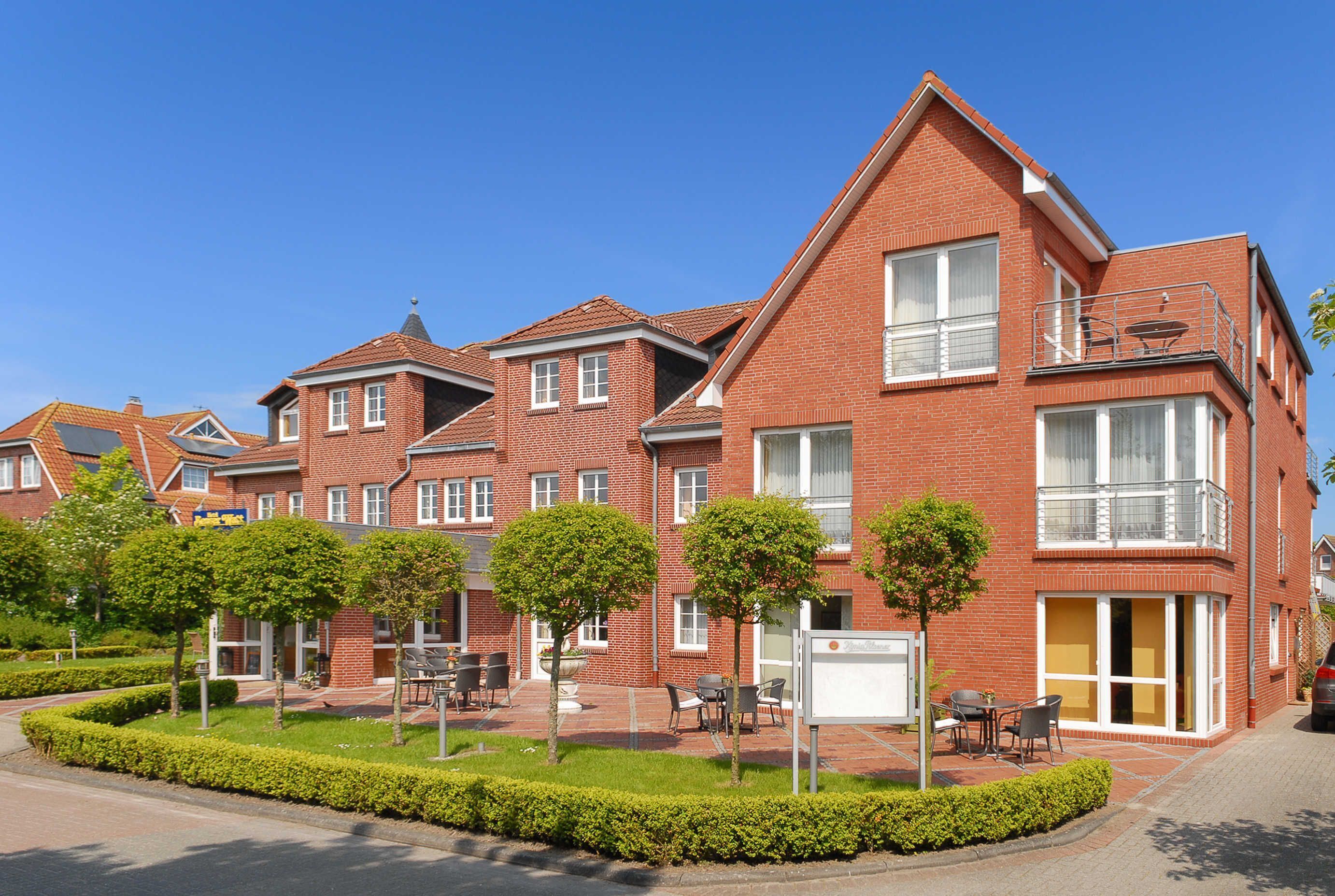 A row of red brick townhouses with balconies, a paved courtyard, and outdoor seating.