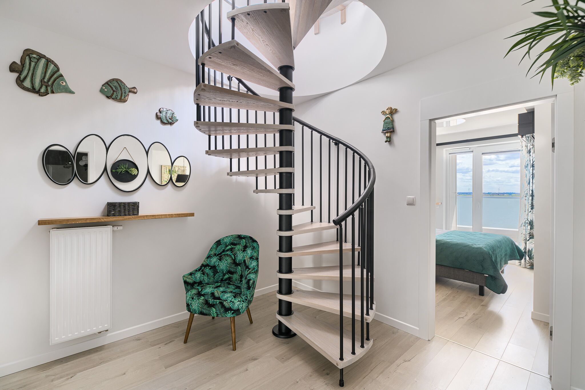 A modern interior with a spiral staircase, a green chair, and a bed with a green bedspread.
