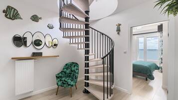 Een modern interieur met een wenteltrap, een groene stoel en een bed met een groene spreideken.