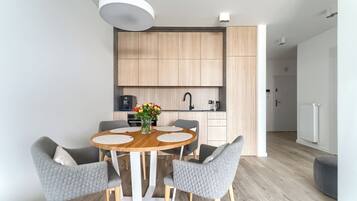 Una cocina moderna con armarios de madera, una mesa redonda con sillas tapizadas en gris, y un jarrón de flores sobre la mesa.