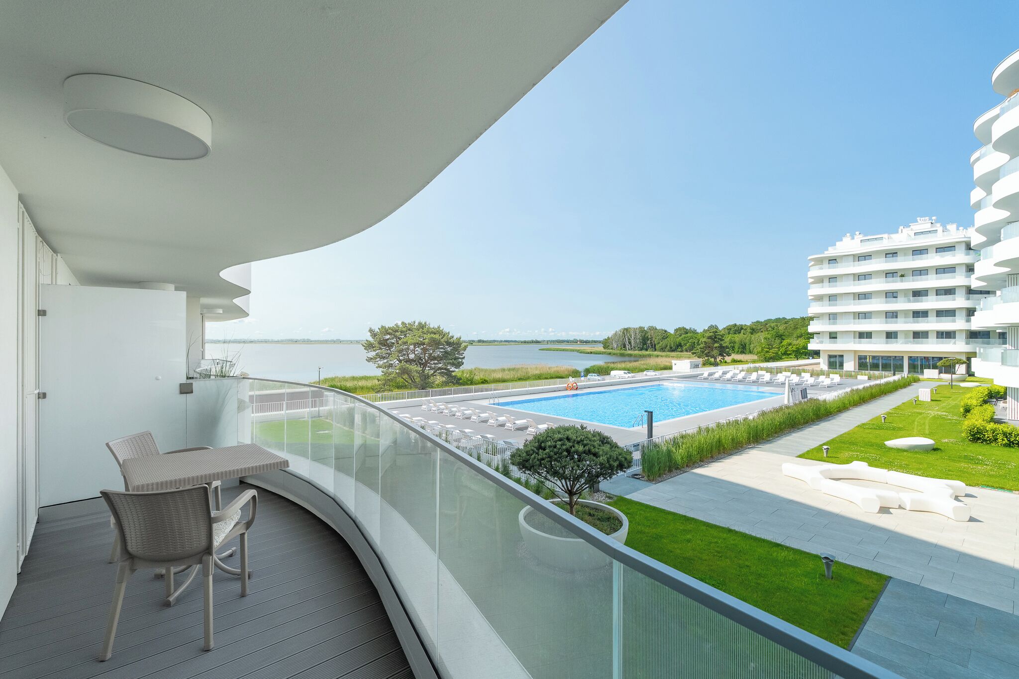 Un balcón con vista a una piscina, un jardín y un edificio moderno.