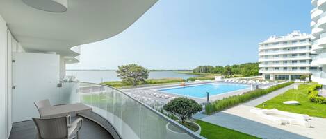 Un balcón con vista a una piscina, un jardín y un edificio moderno.