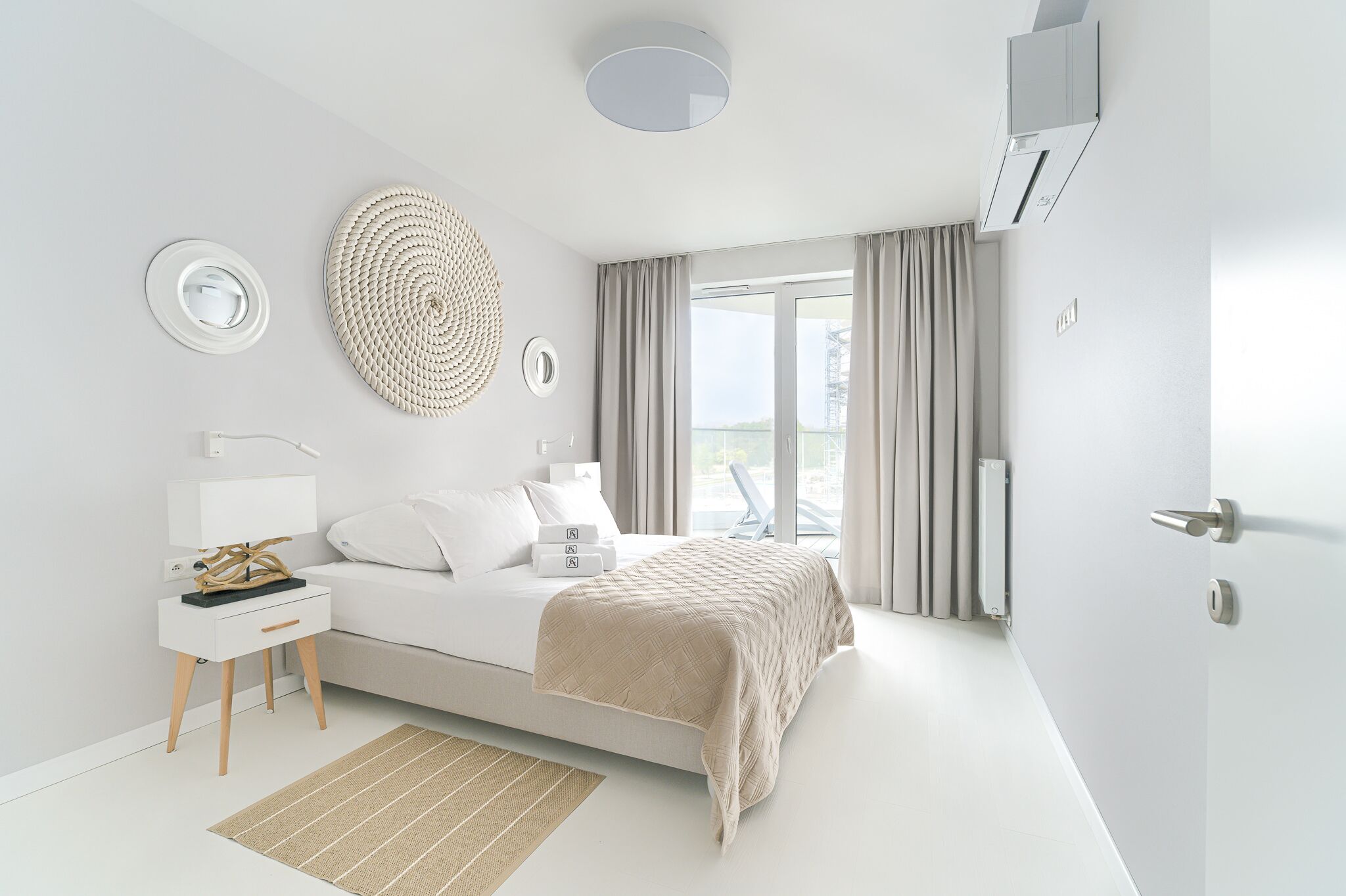 Un dormitorio moderno con cama, mesita de noche y vistas al exterior.