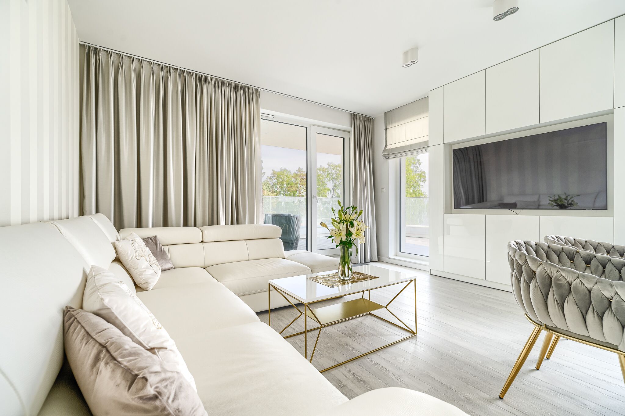 Un salon moderne avec un canapé, une table basse et un fauteuil recouvert d’un tissu gris.