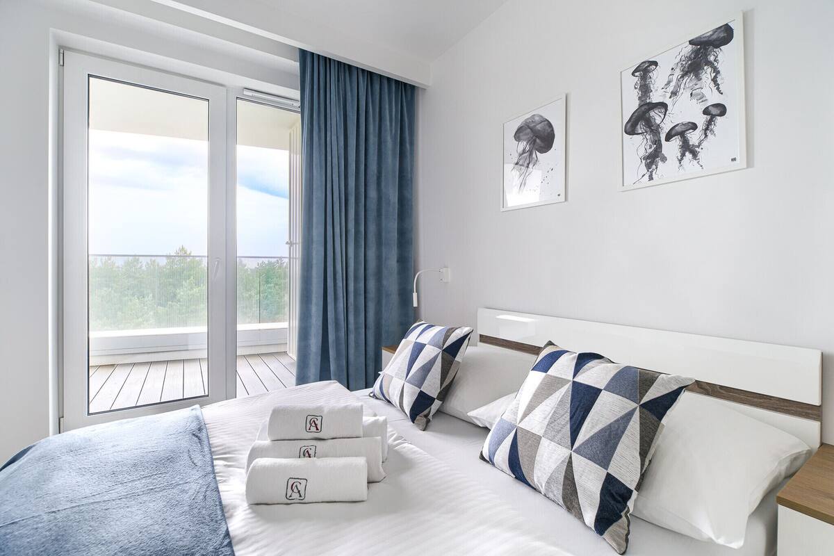 Una habitació d'hotel amb un llit, una finestra gran i vistes a vegetació.