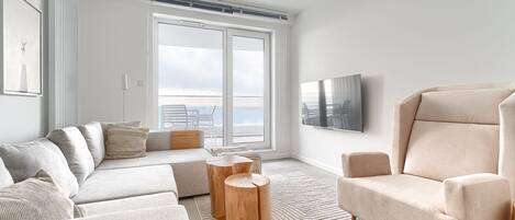 A modern living room with a sofa, armchair, and round wooden side tables.
