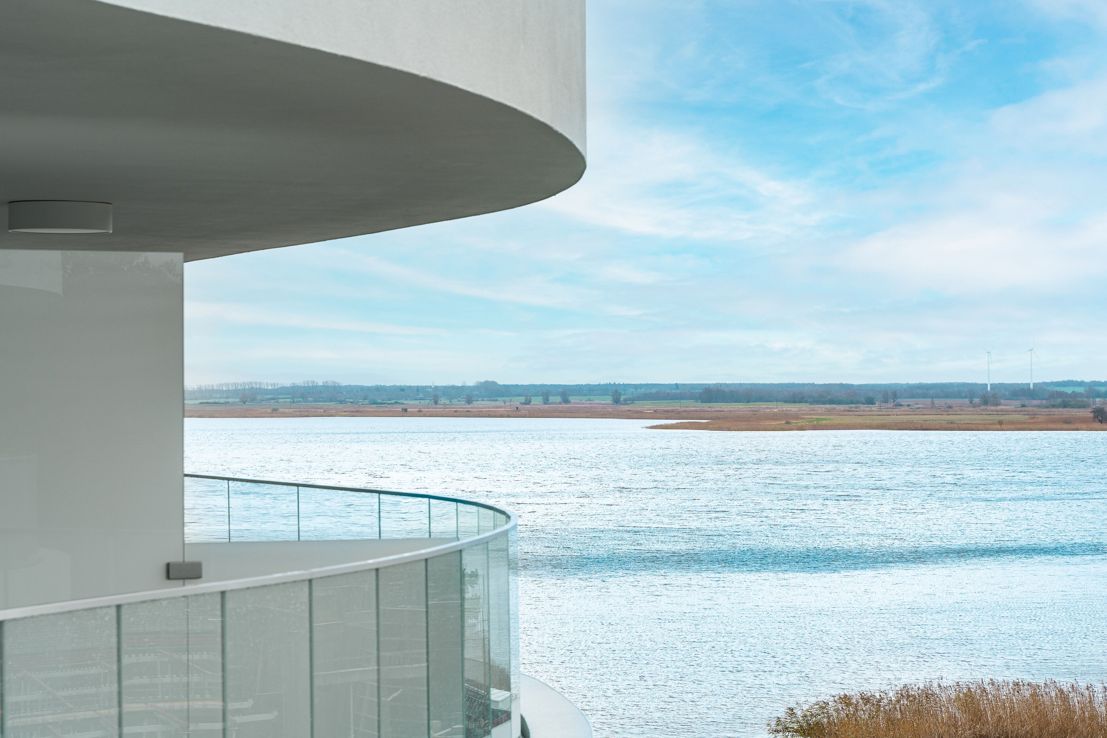 Un edificio moderno con un balcone in vetro che si affaccia su un fiume.