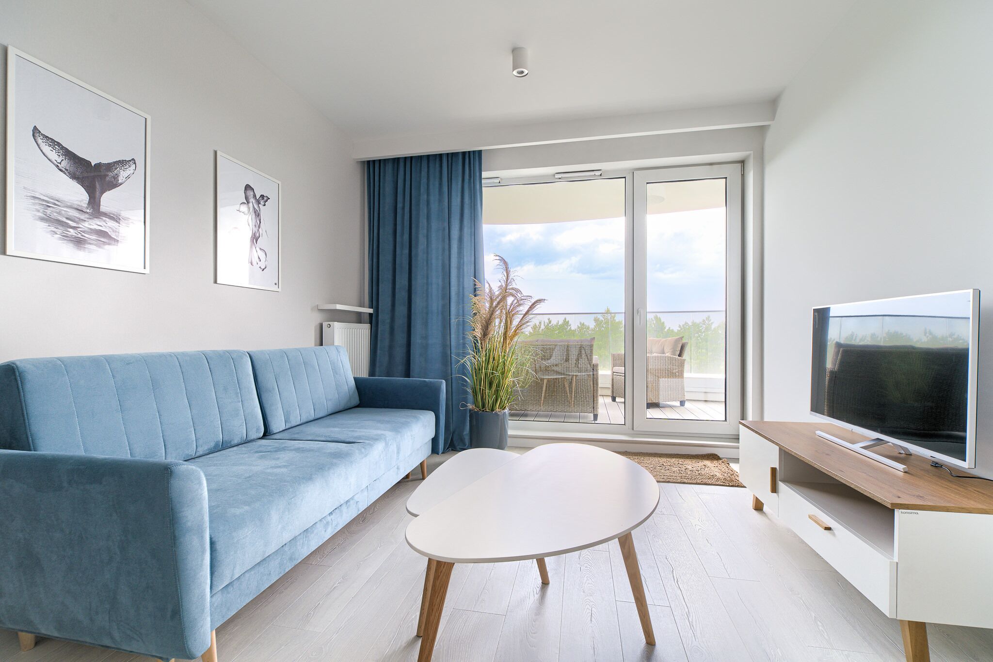A modern living room with a blue sofa, a white coffee table, and a TV on a wooden stand.