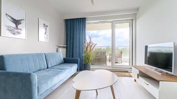 A modern living room with a blue sofa, a white coffee table, and a TV on a wooden stand.