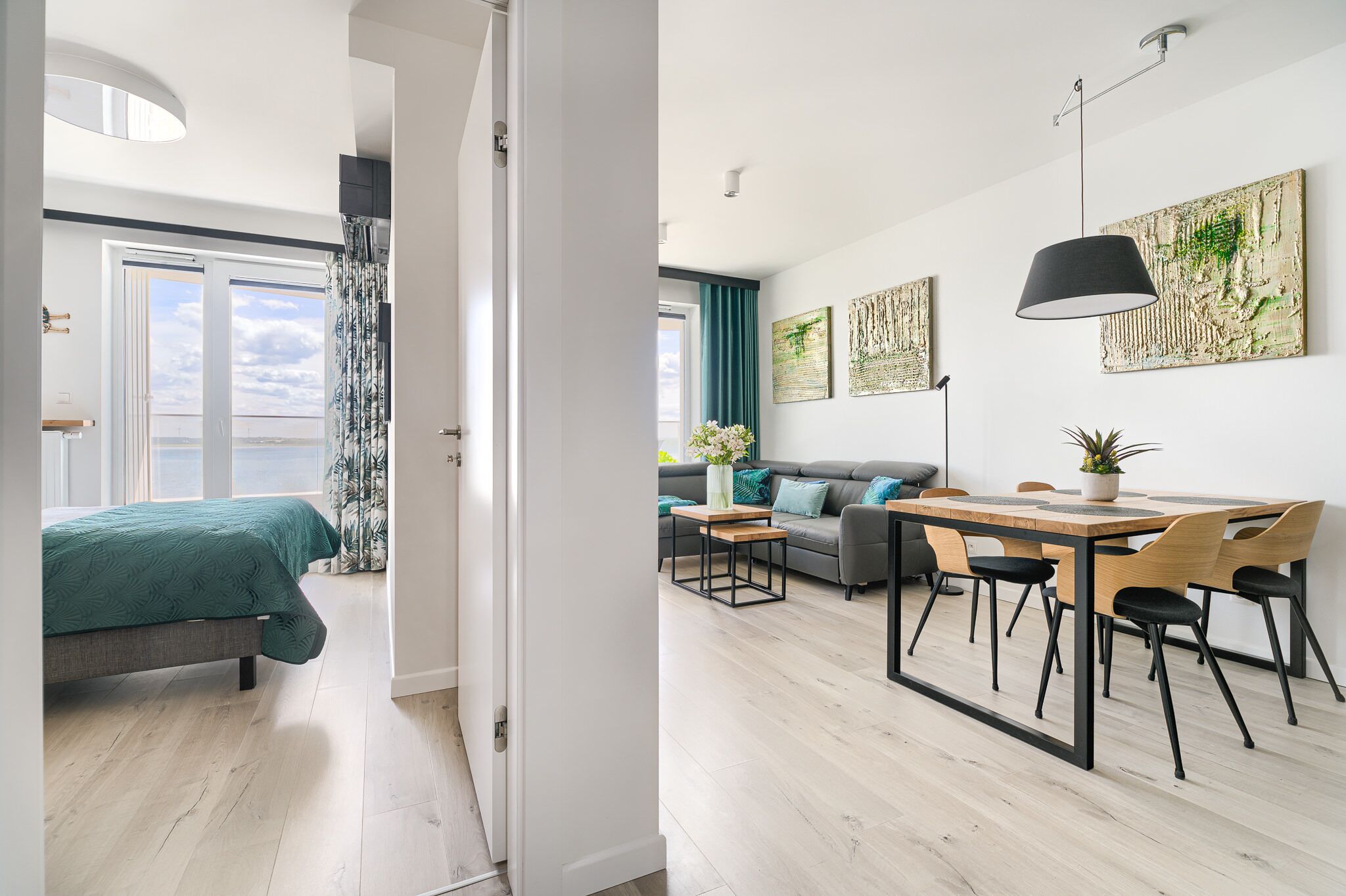 A modern apartment with a large bed, a dining area, and a sofa.