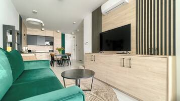 A modern living room with a green sofa, a round coffee table, and a TV mounted on a wooden cabinet.