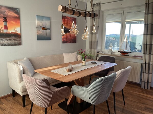 A dining area with a wooden table, cushioned chairs, and a view of a cityscape through a window.