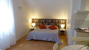 Une chambre à coucher comprenant un lit, deux tables de chevet, une bibliothèque, un bureau et une chaise.
