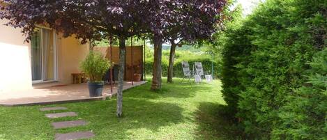 A well-maintained garden with a patio area, outdoor furniture, and a variety of plants.