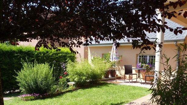 Un jardin avec un espace patio, une table et des chaises, et un m ât pour drapeau.