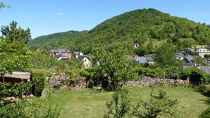 Un village rural aux murs et aux maisons en pierre, avec une colline en arrière-plan.
