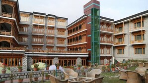 A courtyard with outdoor seating and a multi-story building with balconies. - TIH Hotel Shangrila-Ladakh (Leh)
