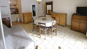A compact living space with a dining table surrounded by chairs, a sofa, a television, and wooden cabinets. - Charming T2 in Barcelonnette with terrace for 4 people (Barcelonnette)