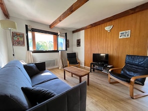 A living room with a sofa, a wooden coffee table, a TV stand, and a chair.