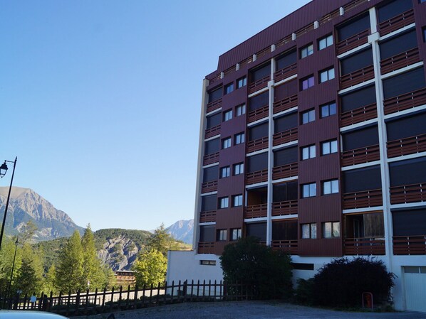 Un edificio de varios pisos con un diseño arquitectónico moderno, que presenta una serie de balcones y ventanas grandes.