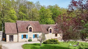 A stone building with a gravel driveway and a grassy lawn.