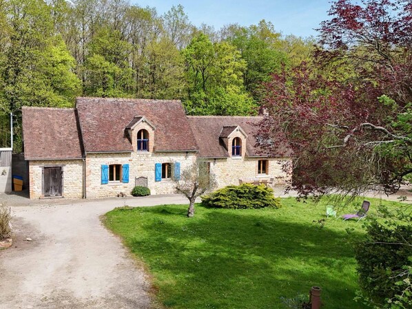 Un bâtiment en pierre avec une allée en gravier et une pelouse verdoyante.