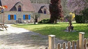 A stone building with a tiled roof, a wooden fence, and a grassy lawn.