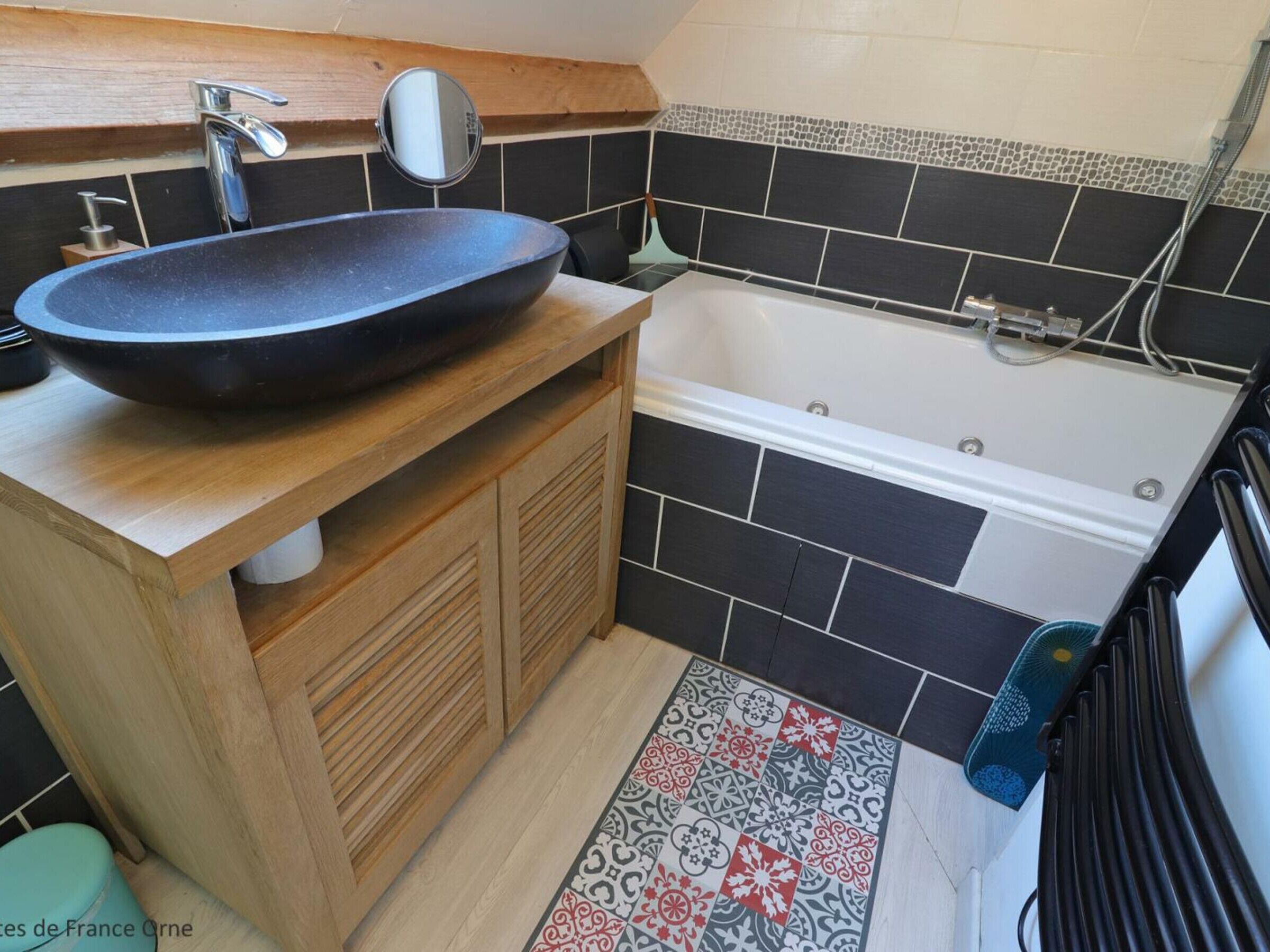 A bathroom with a freestanding bathtub, a sink with a mirror, and a patterned floor.