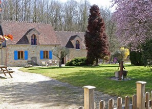 A stone building with a tiled roof, a wooden fence, and a grassy lawn.