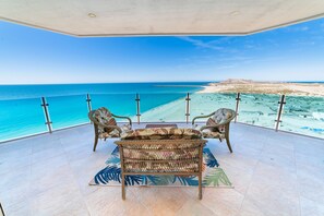 Ein Balkon mit Korbmöbeln und Blick auf den Strand.