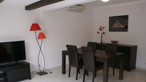 A modern dining area with a TV, two red lamps, and a painting on the wall. - Charming Villa with Terrace, A/C, near Tantra Club, Private Parking (Cap d'Agde naturisme)