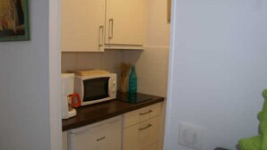 A small kitchen with white cabinets, a microwave, and a sink. - Charming Villa with Terrace, A/C, near Tantra Club, Private Parking (Cap d'Agde naturisme)