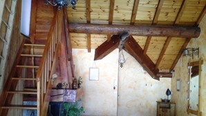 Ein rustikales Schlafzimmer mit einer Holztreppe, einem Bett, einem kleinen Tisch mit Pflanzen und einem Holzschrank.