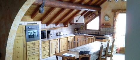 A rustic kitchen with wooden cabinets, a large island, and a vaulted ceiling.
